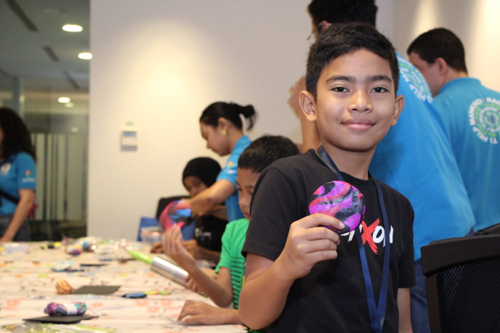 Jiran Ria kid holding a clay coaster he made